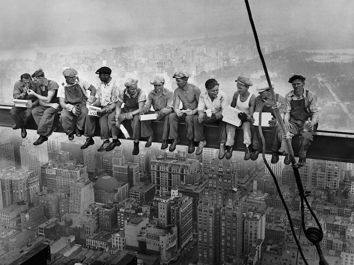 Eleven ironworkers eating lunch on a steel beam high above Manhattan